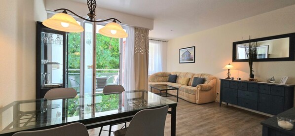 A living room with a glass dining table, a sofa, and a cabinet.