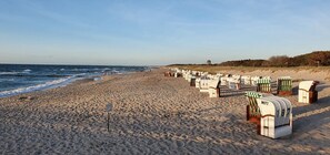 Une plage bordée de rangées de cabanes de plage et d’un panneau indicateur.