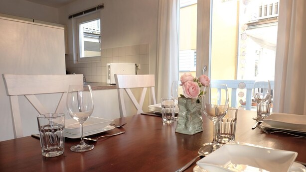 A dining table set with plates, glasses, and cutlery in a well-lit room with a view of the outside.