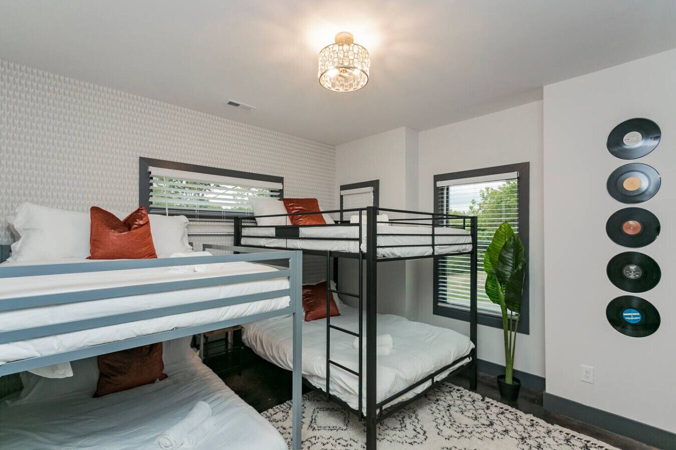 A bunk bed room with a white brick wall, a hanging light fixture, and a plant near the window.