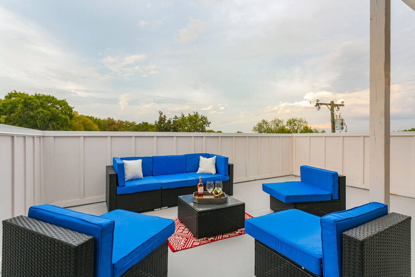 A rooftop patio with a blue sofa set, a coffee table, and wicker chairs.