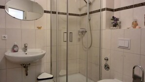 A bathroom with a glass-enclosed shower, a sink with a mirror above it, and a toilet.
