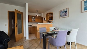 Una cocina moderna con armarios de madera, una mesa de comedor de vidrio y una encimera negra.