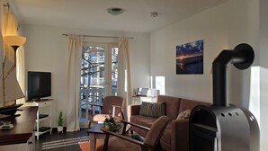 Ein modernes Wohnzimmer mit Fernseher, Sofa und Kamin.