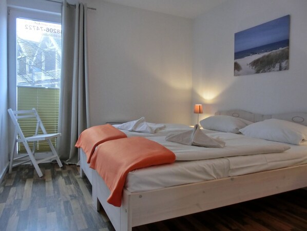 A bedroom with a bed, a chair, a lamp, and a painting on the wall.