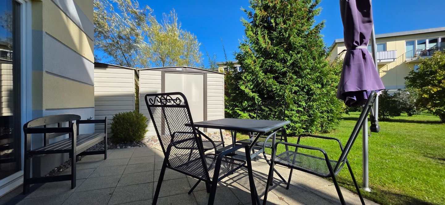 An outdoor patio with a table and chairs, a bench, and a covered umbrella.