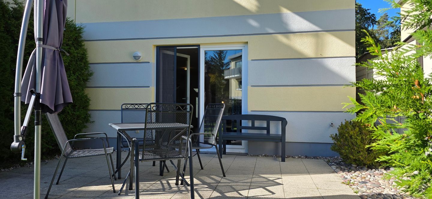 An outdoor patio with a table and chairs, a door, and a small garden area.