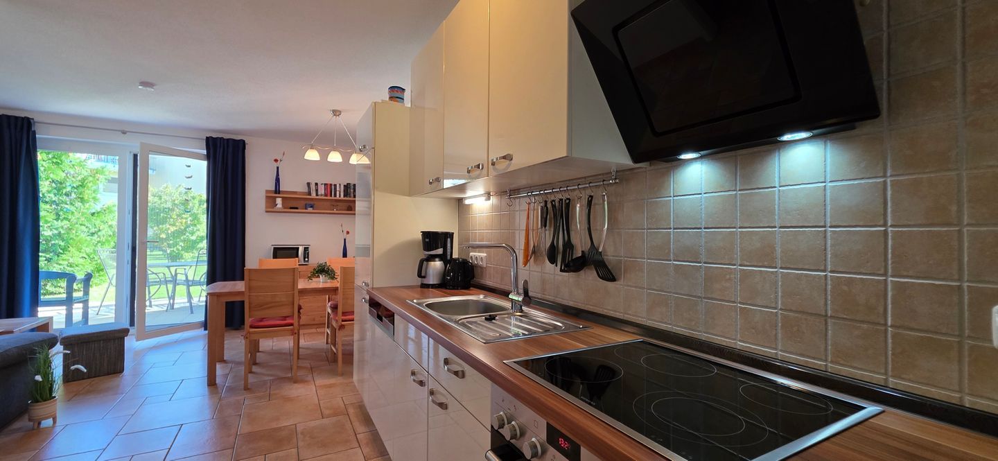 A modern kitchen with a built-in stove, a coffee maker, and a dining area with a table and chairs.