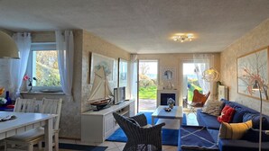Un accogliente soggiorno con divano, tavolo da pranzo e sedie. Presenta un camino e opere d'arte alle pareti.