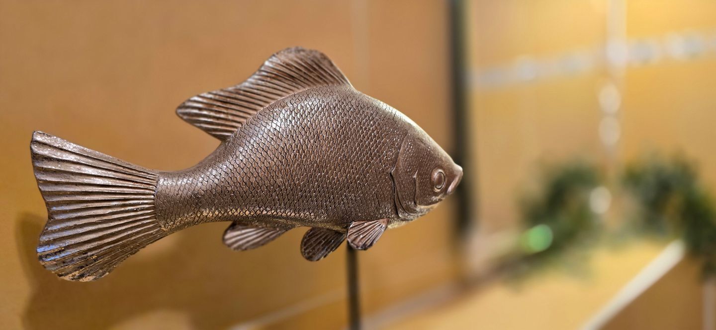 Una escultura de pez con textura detallada de escamas y un ojo prominente.