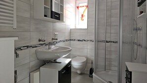 Et moderne badeværelse med vask, toilet og bruser.