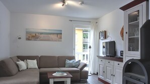 A living room with a sofa, a small table, a television, and a cabinet.