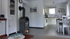 A modern kitchen with white cabinetry, a built-in stove, and a dining area with a wooden table and chairs.