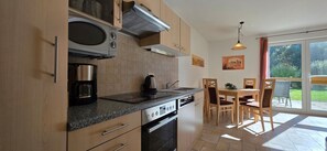 A modern kitchen with a built-in oven, microwave, and coffee maker. There is a dining area with a table and chairs.