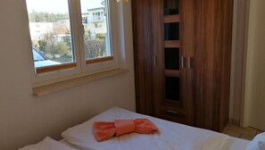 A bedroom with a bed, a window, and a wooden wardrobe.