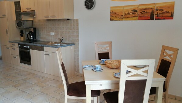 A kitchen with a dining area, including a table set with plates, cups, and a basket.