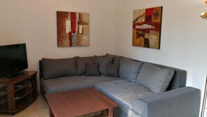 A living room with a grey sectional sofa, a wooden coffee table, and two abstract paintings on the wall.