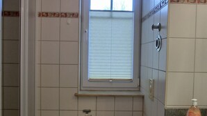 A small bathroom with a toilet, a sink, and a window above the toilet. - Apartment i25 - 56 m² large 3-room apartment 3 pers. on the 1st floor in the house Lee (Graal-Müritz)
