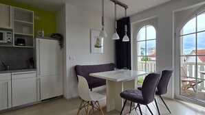 Eine moderne Küche mit eingebauter Mikrowelle, weißen Schränken und einem Essbereich mit einem weißen Tisch und zwei Stühlen.