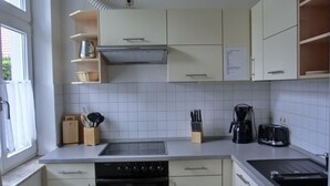 Cocina con estufa, horno, pileta y cafetera. Hay placares y una ventana.