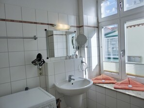 A bathroom with a sink, mirror, towel rack, and a window with blinds.