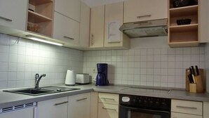 A kitchen with white cabinets, a sink, a coffee maker, and an oven. - Vacation apartment LVC11 - 2-room apartment for 4 pers. with WLAN, pets allowed (Graal-Müritz)