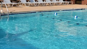 A swimming pool with clear blue water, surrounded by white lounge chairs and a wooden fence. - ABOUT 5 BLOCKS FROM THE BEACH/ OCEAN / NORTH END OF BOARDWALK (Ocean City)