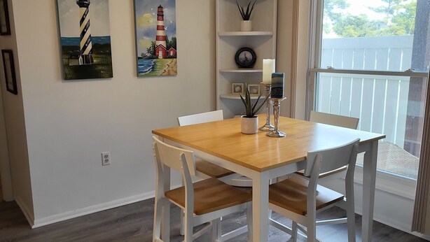 A dining area with a wooden table and white chairs, a ceiling fan, and two paintings of lighthouses on the wall. - ABOUT 5 BLOCKS FROM THE BEACH/ OCEAN / NORTH END OF BOARDWALK (Ocean City)