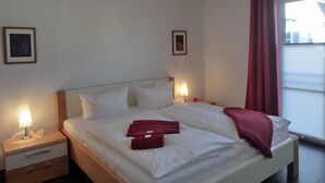 A hotel room with a bed, bedside tables, lamps, and two framed pictures on the walls. - Vacation apartment L31- "Fürstenhof" - 2-room apartment for 4 people on the 2nd floor with WLAN (Graal-Müritz)