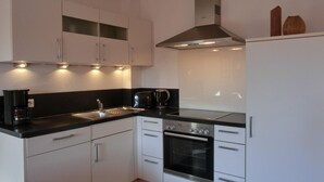 A modern kitchen with white cabinets, a black countertop, a stainless steel range hood, and a built-in oven. - Vacation apartment L31- "Fürstenhof" - 2-room apartment for 4 people on the 2nd floor with WLAN (Graal-Müritz)