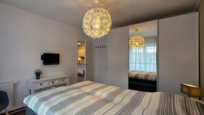 A modern bedroom with a large bed, a TV, a desk, and a mirror. - Apartment L28 - 2-room apartment on the 2nd floor, approx. 45 m² for 4 persons with WLAN (Graal-Müritz)