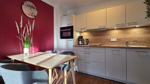 A compact kitchen with white cabinets, a wooden countertop, and a red accent wall. - Apartment L28 - 2-room apartment on the 2nd floor, approx. 45 m² for 4 persons with WLAN (Graal-Müritz)