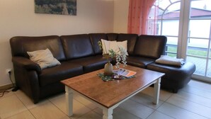 En stue med en mørkebrun lædersofa, et træsofabord og et billede på væggen.