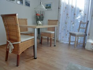 Un coin repas avec des chaises en osier, une table et un vase rempli de fleurs.