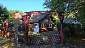 Une maison traditionnelle en bois, avec un toit rouge, un petit porche et une pancarte indiquant « accès libre aux propriétés adjacentes ».