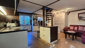 Un espace de vie compact comprenant un coin cuisine, un coin repas et un espace détente avec un canapé et une table basse.