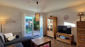 Una sala de estar con sofá, televisor, aparador de madera y lámpara.