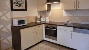 Una cucina compatta con microonde, macchina del caffè, tostapane, piano cottura, forno e lavastoviglie.