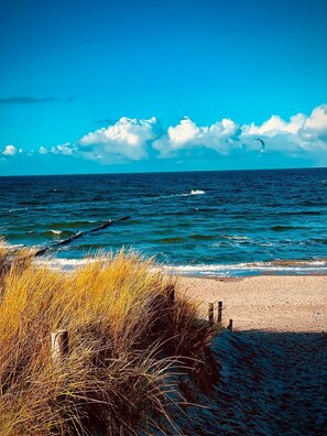 Une plage avec un ciel dégagé, un rivage sablonneux et une étendue d’eau.