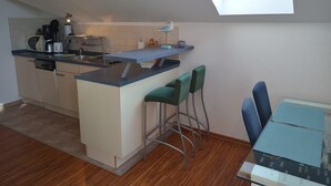 A compact kitchen with a skylight, a dining area with two chairs, and a small table.