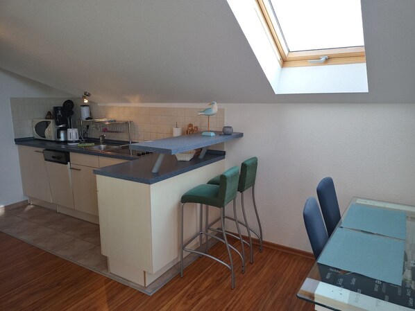 A compact kitchen with a skylight, a dining area with two chairs, and a small table.