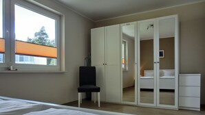 Quarto com cama, poltrona, guarda-roupa e janela.