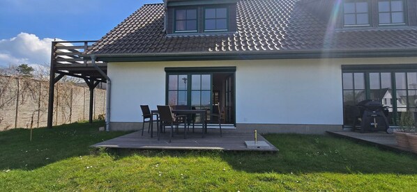 A house with a patio, a covered outdoor seating area, and a garden.