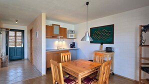 Una cucina compatta con mobili in legno, un tavolo da pranzo e una lampada a sospensione.