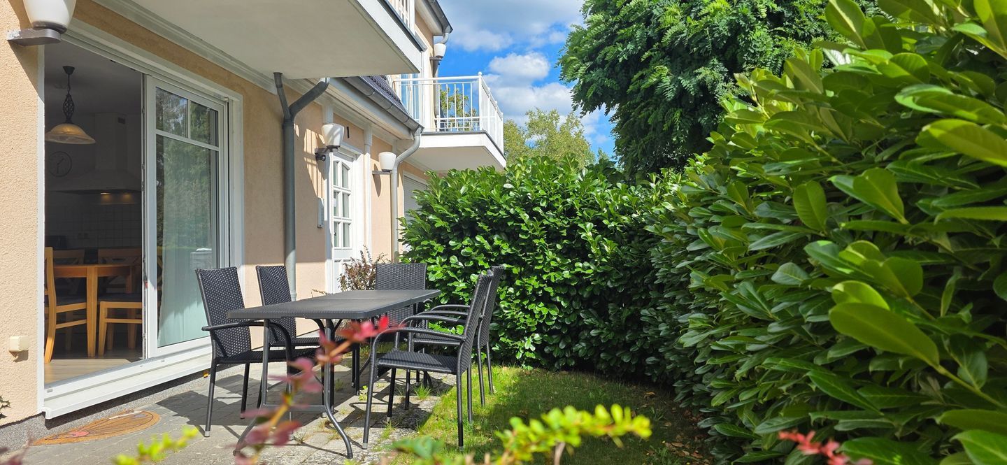A patio with a table and chairs, a sliding glass door, and a balcony with a railing.