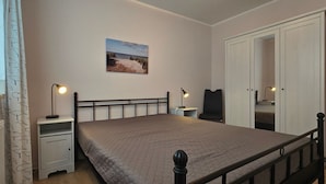 Une chambre à coucher comprenant un lit, des tables de chevet, une armoire et un tableau accroché au mur.