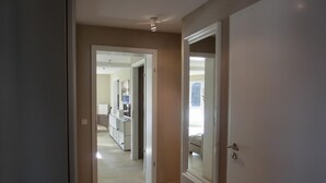 Un couloir menant à une chambre dotée d’un grand miroir et d’une porte.