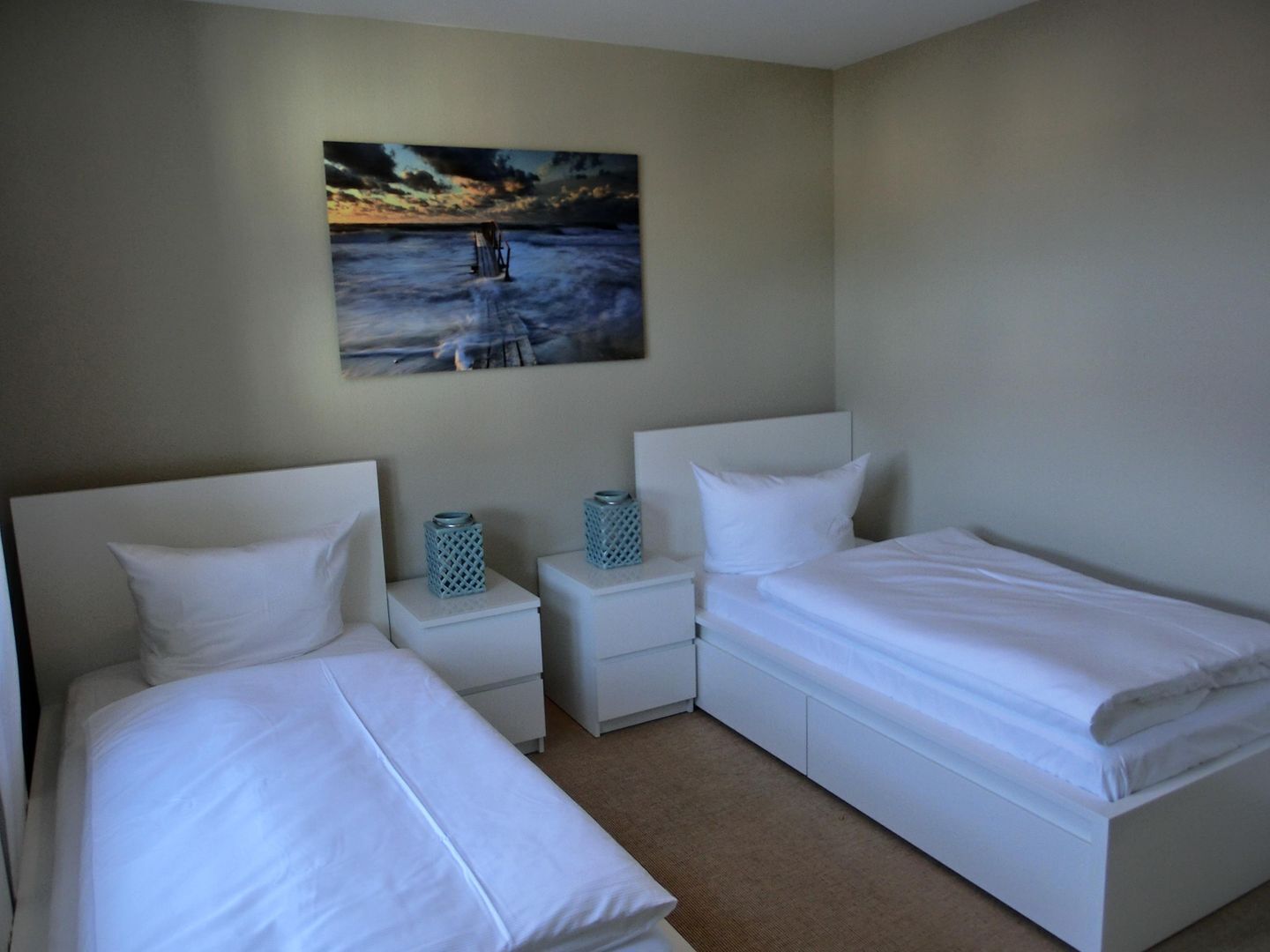 Ein Hotelzimmer mit zwei Einzelbetten, einem Nachttisch mit Lampe und einem Gemälde an der Wand.