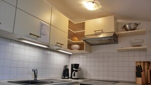 A modern kitchen with white cabinets, a built-in oven, a coffee maker, and a sink. - Vacation apartment LVC4 - 2-room apartment for 4 pers. with WLAN (Graal-Müritz)