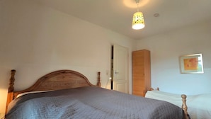 Um quarto com uma cama de madeira, um abajur, uma porta e um quadro na parede.